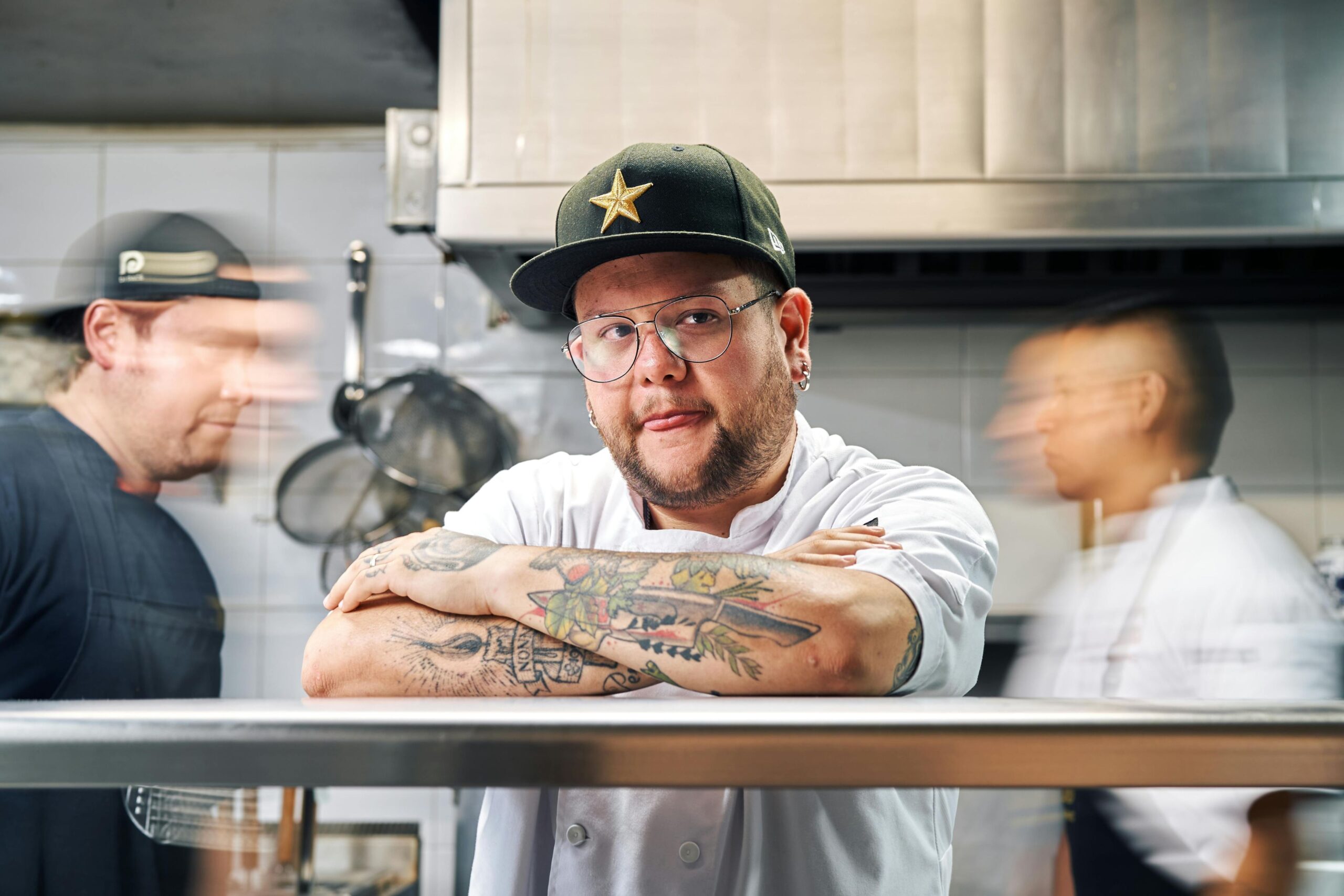 chef profissional com tatuagens nos braços na pass na cozinha