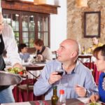 Professional waiter serving a plate at a restaurant table, representing waiter respect in hospitality