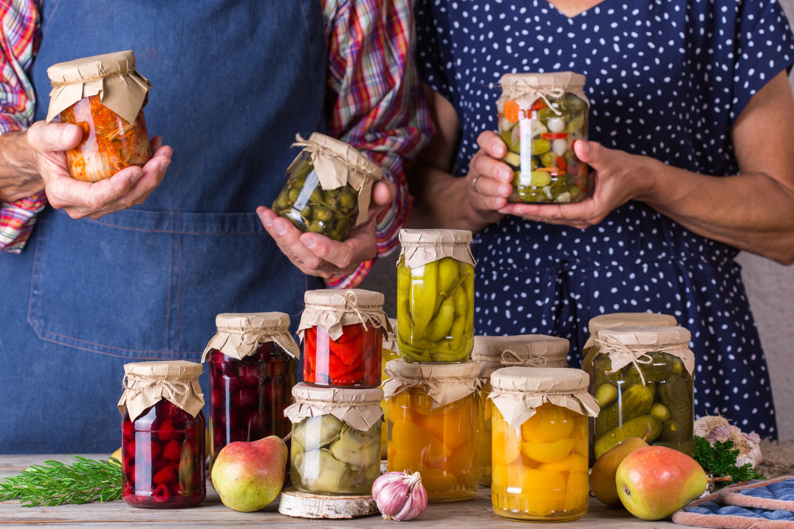 homem e mulher apresentam potes de vegetais fermentados