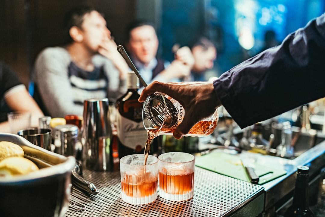 Um bartender serve uma amostra de destilado premium no Festival de Comida, cercado por visitantes entusiasmados em um evento ao ar livre.