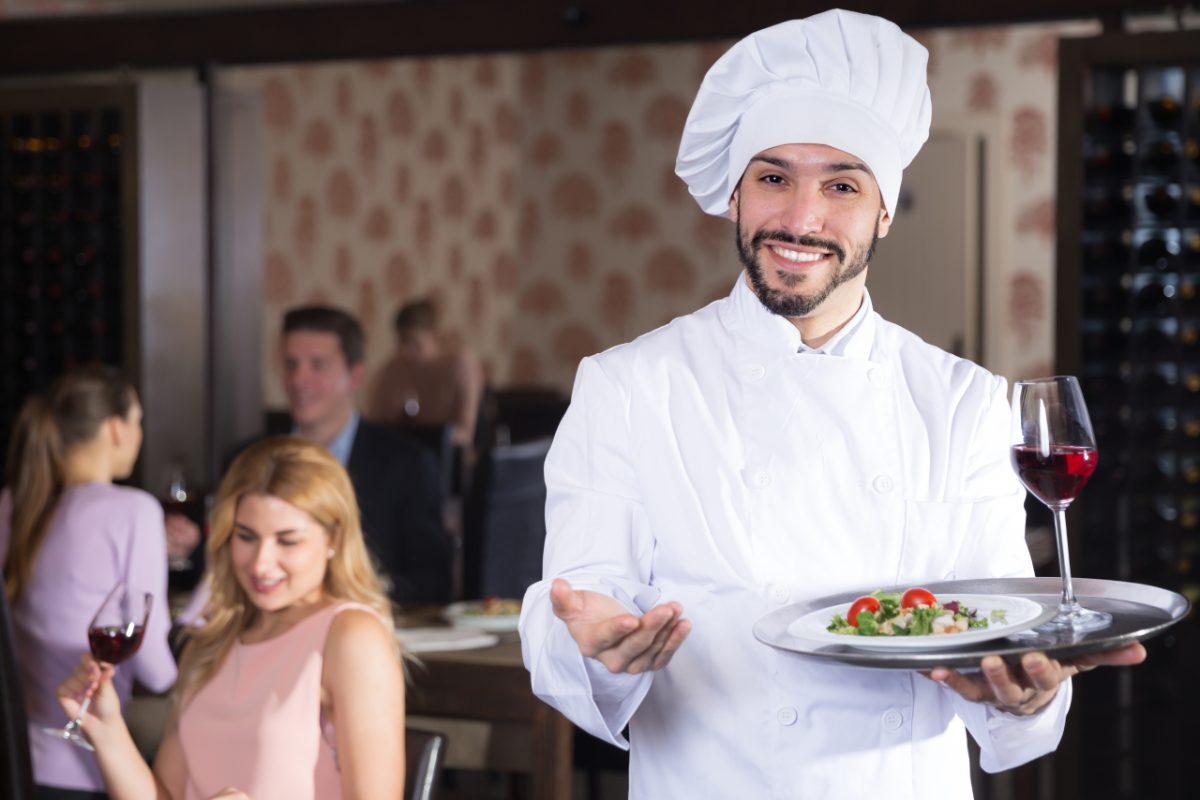 Un chef quitte sa petite cuisine de restaurant pour accueillir ses clients fidèles à leur table