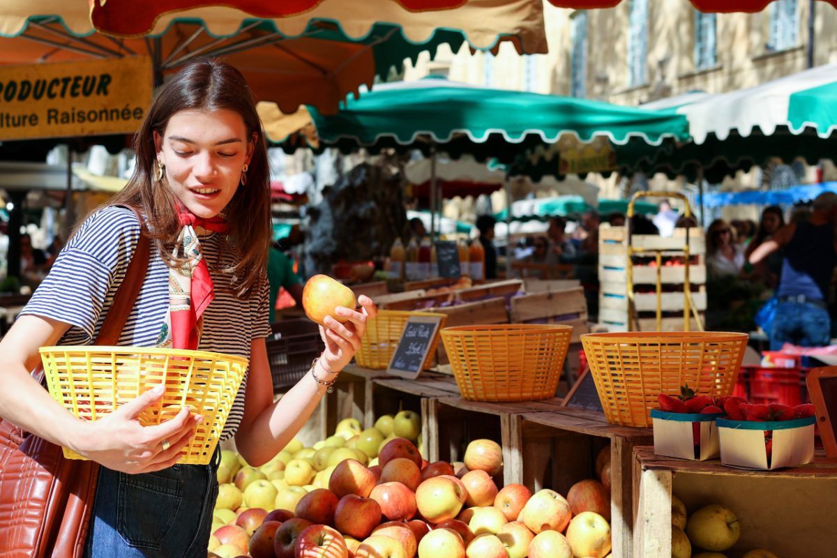 Uma mulher organizando cuidadosamente frutas de caroço maduras em um mercado de agricultores de verão, selecionando os melhores pêssegos e ameixas para armazenamento