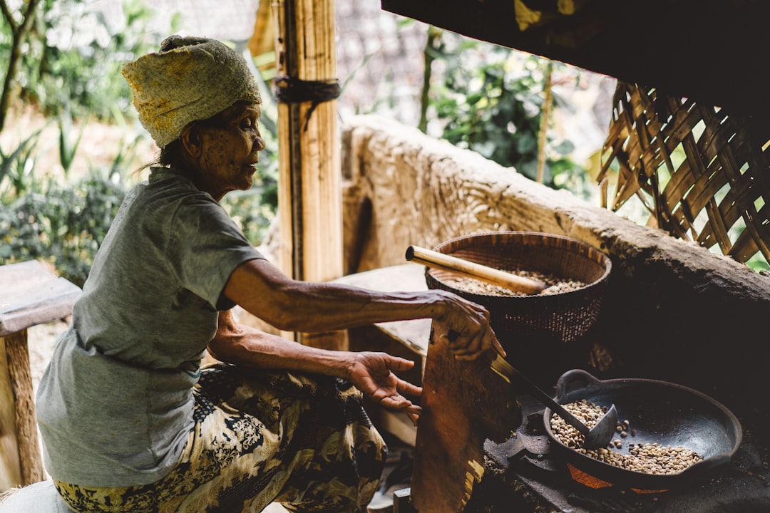 Une femme moulant soigneusement des mélanges d'épices aromatiques africains à l'aide d'un mortier et pilon en pierre traditionnels dans une cuisine familiale