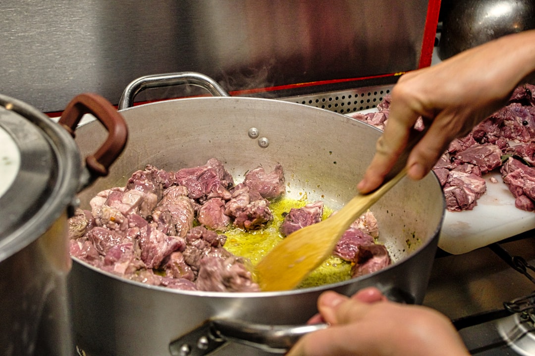 Um chef cuidando cuidadosamente de cozidos lentos em uma caçarola pesada, demonstrando técnica clássica em fogo baixo