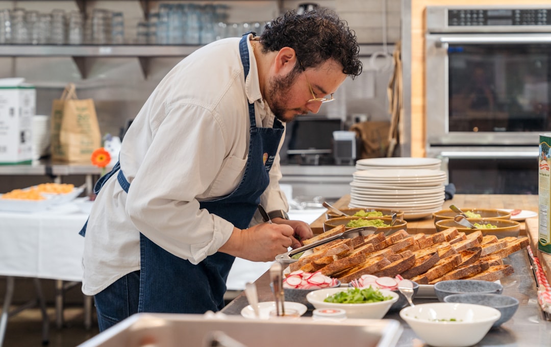 A hotel chef carefully plates a locally sourced hotel breakfast dish featuring seasonal vegetables and regional grains