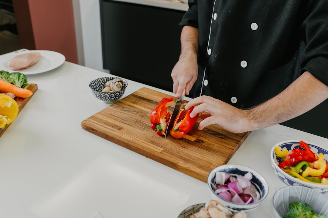 Um chef demonstrando habilidades com a faca enquanto fatia tomates de verão frescos em uma tábua de corte de madeira