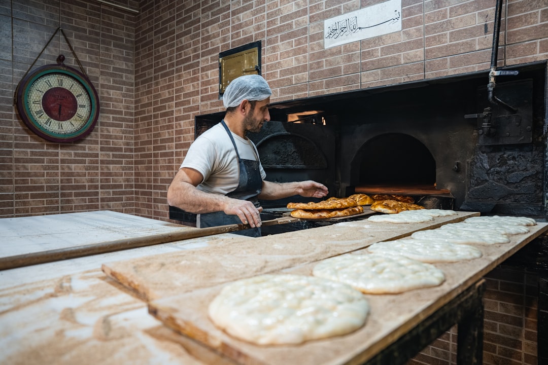 Un uomo che preme i pani contro il muro di un forno tradizionale in argilla, che dimostra l'antico mestiere della preparazione dei pani.