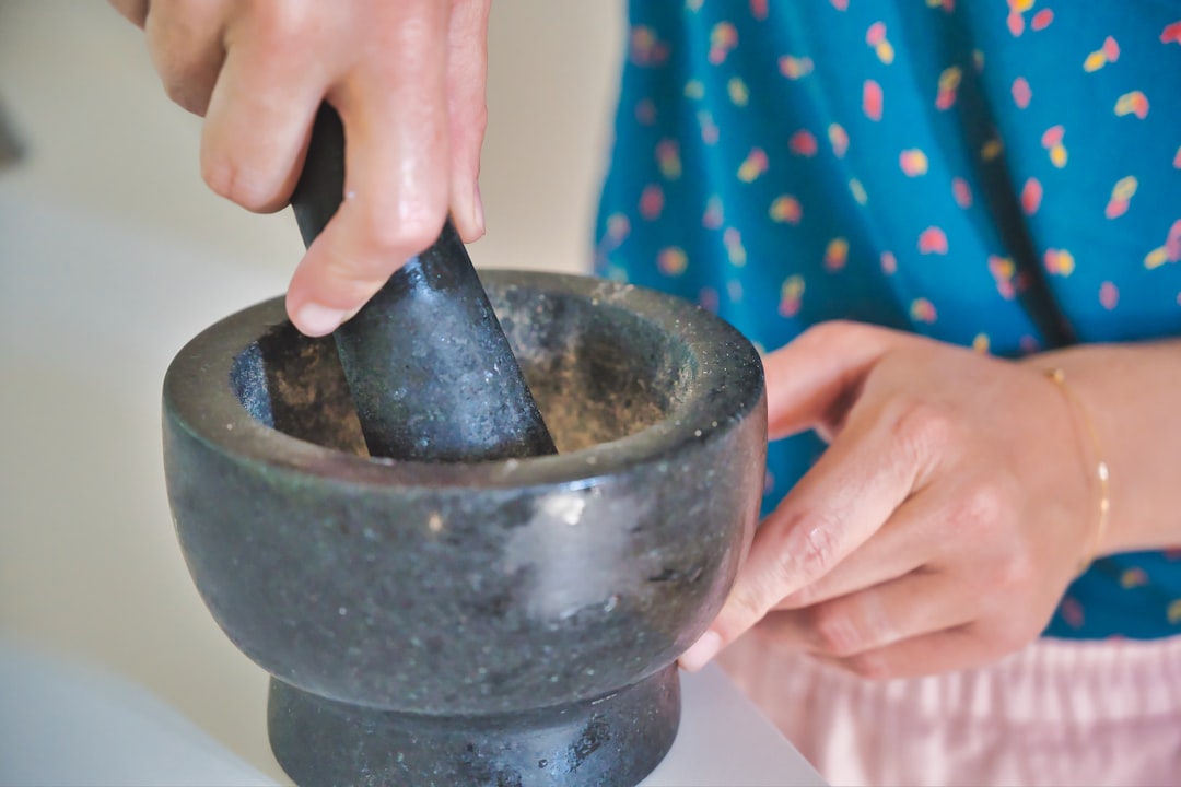 A woman grinding fresh cilantro and parsley in a mortar while preparing Moroccan chermoula from scratch