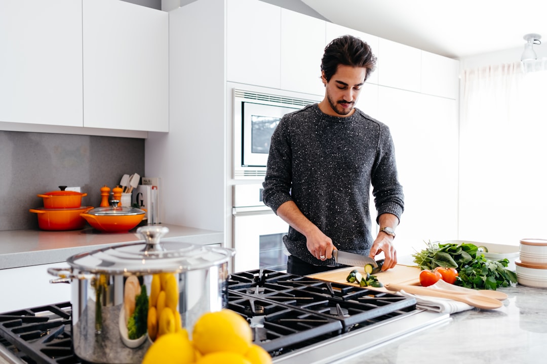 A professional chef finely chopping fresh parsley to prepare a classic green sauce at a wooden kitchen counter