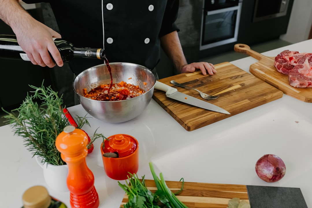 Um chef misturando ingredientes básicos de marinada, incluindo óleo, frutas cítricas e ervas frescas em uma tigela grande de cerâmica