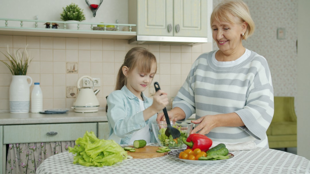 Uma mulher temperando cuidadosamente saladas de grãos geladas em uma cozinha iluminada, exibindo técnica culinária global