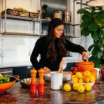 uma mulher organiza legumes assados em um prato como parte do novo serviço de menus de outono em uma cozinha.