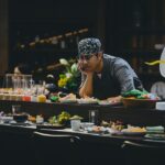 Um membro da equipe de jantar do hotel prova um novo prato durante uma sessão de treinamento pré-serviço, construindo conhecimento sobre os ingredientes.
