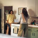 Uma mulher organizando cuidadosamente uma seleção de condimentos globais na prateleira de uma despensa de cozinha bem organizada
