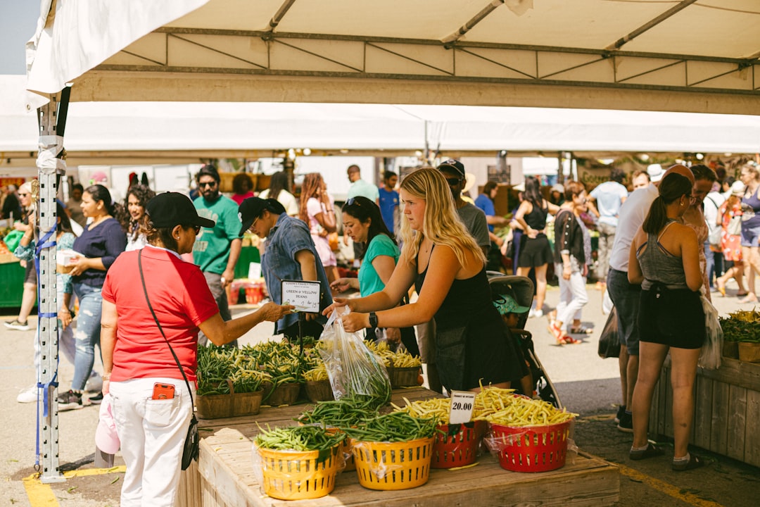 Una donna che seleziona verdure stagionali ai mercati del raccolto in Europa durante settembre, con casse di prodotti freschi disposte.